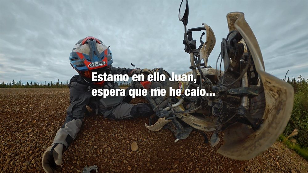 Andrés caído en el suelo junto a su moto en una pista de grava, con el texto: estamo en ello Juan, espera que me he caío